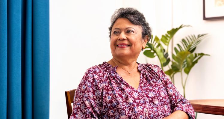 A woman sits next to a table with a glass of water