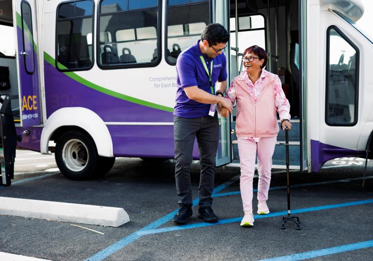 Driver assisting a senior woman stepping off a transport shuttle