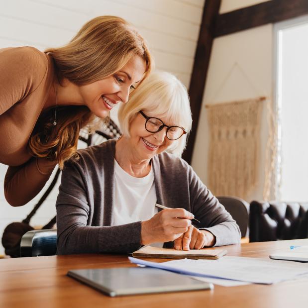 Woman Helping Elderly Woman to Write