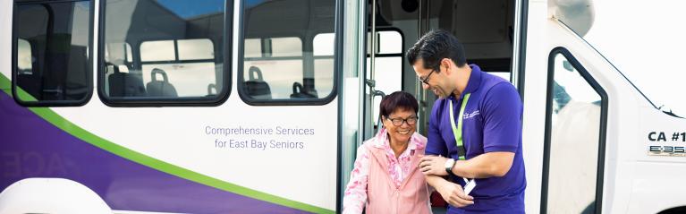 Caregiver Helping Lady Down a Bus