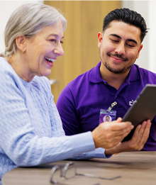 Woman and Helper Smiling at Tablet