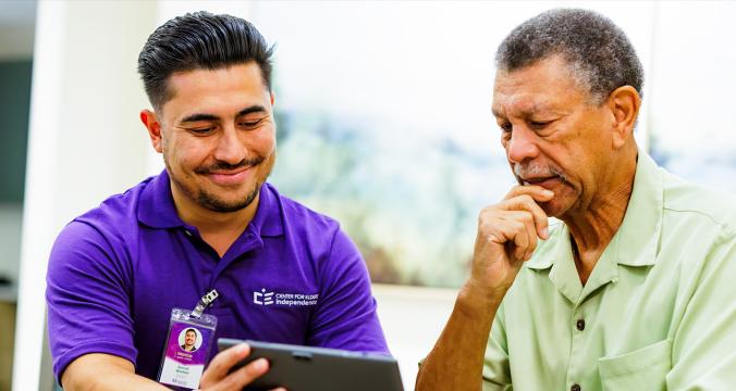 Elderly with Helper Looking at Tablet