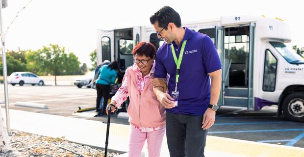 Caregiver Helping Woman off the Bus